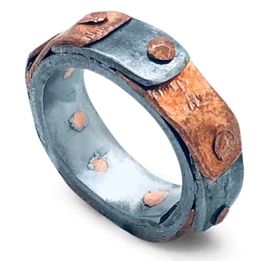 Handgefertigter Pangolin Conservation Snare Ring von Mulberry Mongoose aus kupferfarbenem und silbergrauem Metall, mit breiten überlappenden Metallstreifen und sichtbaren Nieten, auf weißem Hintergrund.